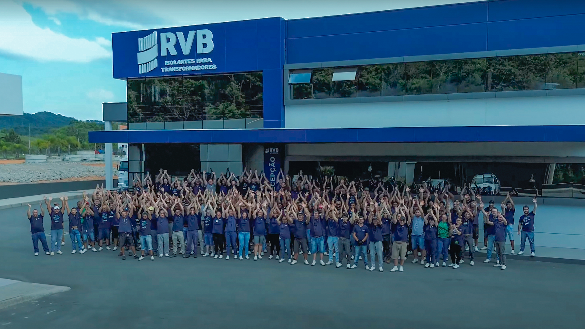 funcionários na frente da empresa com os braços levantados